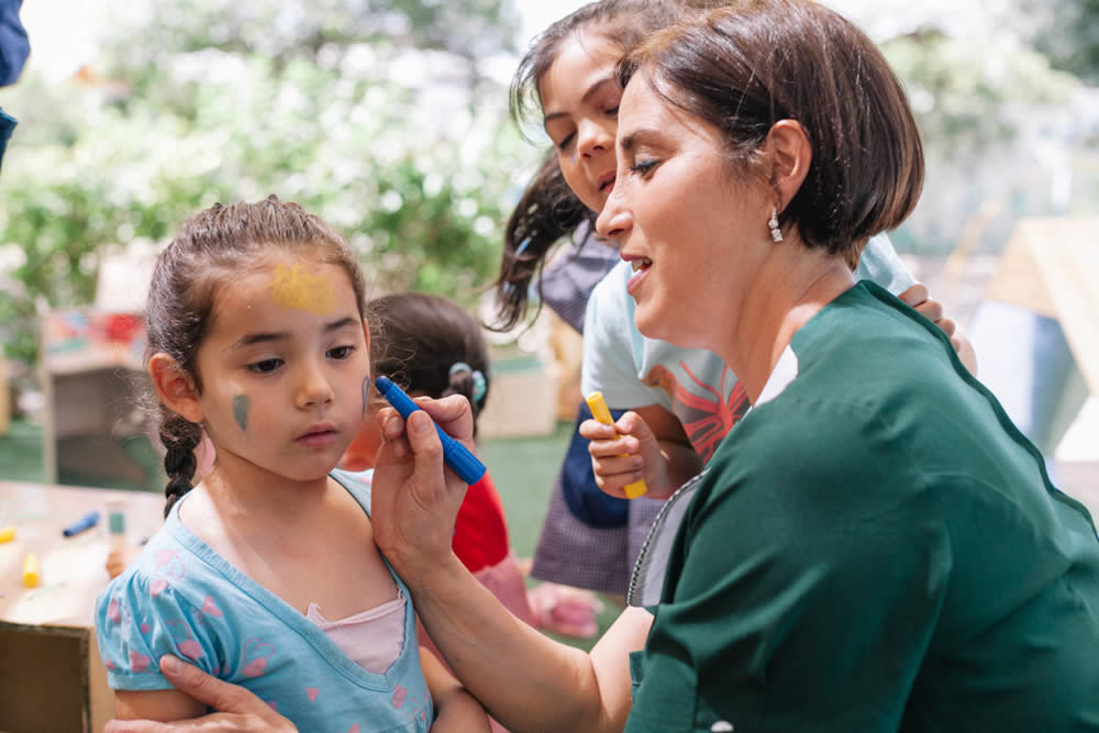 Educadora acompañando a una niña en una actividad artística